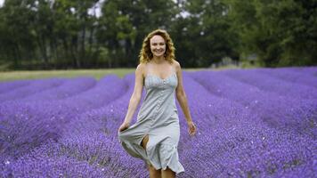 ung kvinna i en blå klänning gående genom lavendel- fält. handling. skön flicka i provence, Frankrike. foto