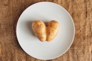 hjärta formad potatisar på rustik Linné bakgrund. ful mat. foto