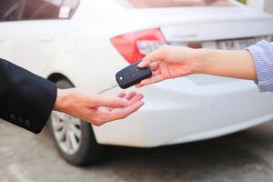 företag hand ger en nyckel för köpare eller uthyrning bil. foto