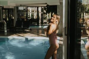 ung kvinna stående förbi de inomhus- simning slå samman foto