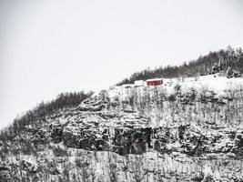 ensamt rött hus på berget på vintern i norge. foto