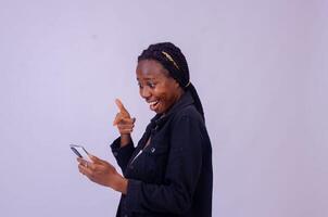 skön ung afrikansk lady pekande till henne telefon skärm i spänning foto