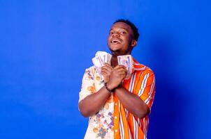 Lycklig och upphetsad ung afrikansk man innehav buntar av kontanter foto
