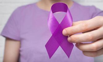 värld cancer dag. en kvinna innehar en lila band i henne hand. anti-cancer tejp. foto
