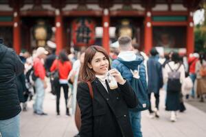 turist kvinna besök sensoji tempel eller asakusa kannon tempel är en buddist tempel belägen i asakusa, tokyo japan. japansk mening på röd lykta betyder åska Port. foto