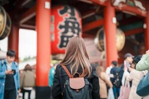 turist kvinna besök sensoji tempel eller asakusa kannon tempel är en buddist tempel belägen i asakusa, tokyo japan. japansk mening på röd lykta betyder åska Port. foto