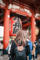 turist kvinna besök sensoji tempel eller asakusa kannon tempel är en buddist tempel belägen i asakusa, tokyo japan. japansk mening på röd lykta betyder åska Port. foto