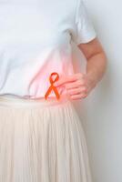 kvinna har tillbaka buk smärta med orange band. njure cancer medvetenhet Mars månad, sjukdom av urin- systemet och stenar, cancer, kronisk njure, urologi, njur- och transplantation begrepp foto