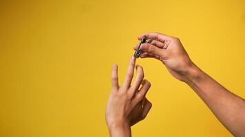mannens hand innehav nagel klippare med både händer isolerat i rosa bakgrund foto