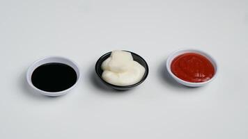 tre såser ketchup majonnäs, ljuv soja sås och chili sås i svart skål isolerat på vit bakgrund foto