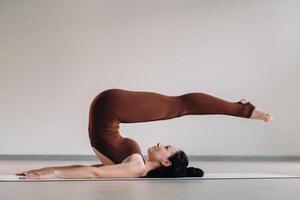 en kvinna i en brun kostym gör yoga i en kondition rum . friska livsstil, kondition, Träning, egenvård foto