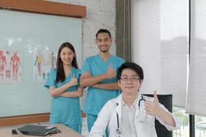 vårdgrupp, porträtt av tre unga läkare av asiatisk etnicitet i uniform med stetoskop, leende och titta på kameran i kliniken, personer som har expertis inom professionell behandling. foto