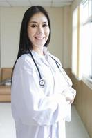 porträtt av smart kvinnlig läkare med ett stetoskop stående vid receptionen på sjukhuset. foto