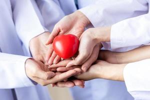 grupp händer som håller ett rött hjärta. läkarnas hand. donera och försäkring, försäkring hälsovård, kärlek, familjeförsäkring och csr-koncept foto