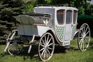 ett antik vit transport från de nittonde århundrade på en grön gräsmatta. de prototyp av en modern bil. foto