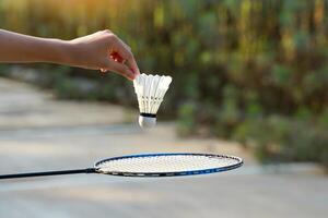 asiatisk flicka innehav en vit fjäderboll till släpp in i de badminton racket Nedan. mjuk och selektiv fokus. foto