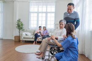 asiatisk ung sjuksköterska Stöd par senior äldre man och kvinna i en rullstol. äldre mogna och en grupp av senior vänner levande i de sjukhus. umgänge av pensionerad människor. foto