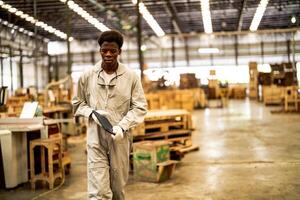 afrikansk man arbetare teknik stående med förtroende med arbetssätt svit klänning och hand handske i främre maskin. begrepp av smart industri arbetstagare fungerar. trä fabrik producera trä gom. foto