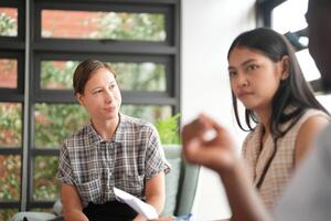 olika anställda samlade in i kontor har roligt under brainstorming medan diskuterar ny idéer projekt. raser medarbetare möte på coworking Plats område. team av ung människor i kontor. foto