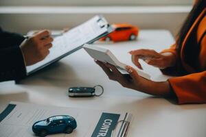 närbild asiatisk manlig människor bil försäljare eller försäljning chef erbjudanden till sälja en bil och förklarar och läser de villkor av signering en bil kontrakt och försäkring. foto