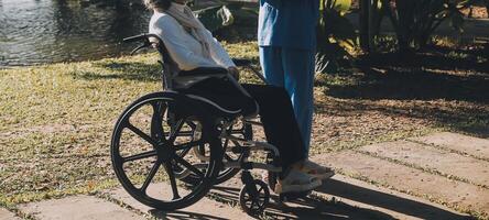 amning personal talande till ett äldre person Sammanträde i en rullstol. foto