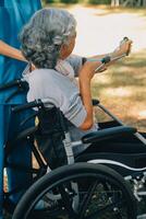 ung sjuksköterska eller fysioterapeut i scrubs portion en Lycklig pensionerad gammal kvinna do kondition övningar med ljus vikt hantlar på Hem. begrepp av fysioterapi för seniors foto