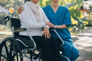 en sjuksköterska ta vård en senior manlig på rullstol i hans trädgård på Hem foto