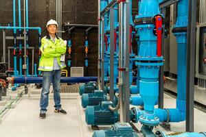 asiatisk man arbetstagare i skyddande enhetlig och med Hardhat använder sig av läsplatta för kontroll temperatur i rör fabrik interiör. foto