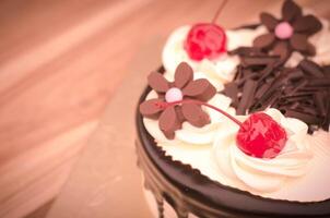 födelsedag kaka, vanilj choklad körsbär var dividerat bitar på en trä- tabell. foto