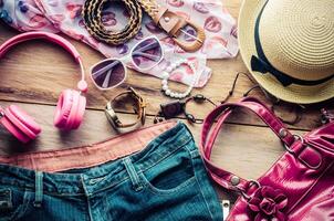 Tillbehör för Tonårs flicka på henne semester, hatt, eleganta för sommar solglasögon, läder väska, skor och kostym på trä- golv. foto