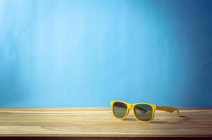 solglasögon vilar på de trä- golv med blå bakgrund. Tillbehör för sommar foto