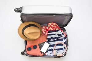 Kläder resenärer pass, plånbok, glasögon, smart telefon enheter, i de bagage redo till resa. foto