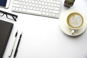 topp se med kopia Plats, arbetssätt skrivbord med bärbar dator, cell telefon, anteckningsbok penna och kaffe på vit bakgrund foto