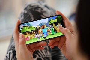 Minecraft mobil ios spel på iphone 15 smartphone skärm i kvinna händer under mobil gameplay foto