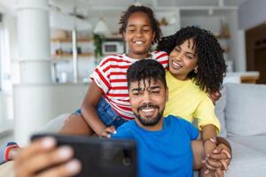 leende far innehav mobiltelefon, framställning selfie skott, inspelning video med Lycklig fru och dotter. upphetsad föräldrar ser på mobil skärm med unge, känsla upphetsad. foto