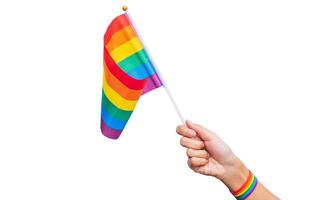 hand med en regnbåge handled rem innehav en regnbåge flagga på en vit bakgrund. Gay stolthet kampanj. Gay stolthet HBTQ begrepp foto