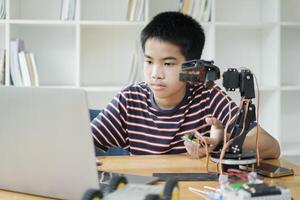 asiatisk tonåring håller på med robot projekt i vetenskap klassrum. teknologi av robotik programmering och stam utbildning begrepp. foto