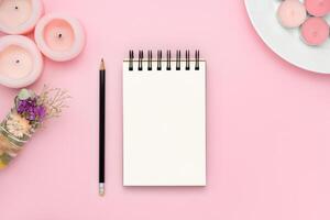 tom anteckningsbok och penna på rosa bakgrund med rosa ljus och fläcka pinne foto