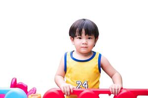 ung barn spelar på färgrik lekplats. asiatisk litet barn pojke i en gul jersey åtnjuter speltid på en vibrerande, färgrik lekplats strukturera, isolerat på vit bakgrund. foto