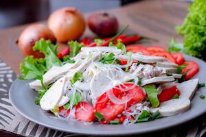 kryddad glas nudel sallad med vietnamese korv eras i en grå tallrik sätta på en trä- tabell och olika grönsaker. foto