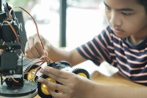 asiatisk tonåring håller på med robot projekt i vetenskap klassrum. teknologi av robotik programmering och stam utbildning begrepp. foto