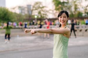 kvinna joggare. passa ung asiatisk kvinna med grön sportkläder aerobics dansa övning i parkera och njuter en friska utomhus. kondition löpare flicka i offentlig parkera. wellness varelse begrepp foto