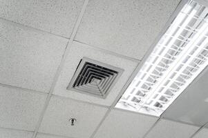 tak monterad kassett typ luft balsam och modern lampa ljus på vit tak. kanal luft balsam för Hem, hall eller kontor. foto
