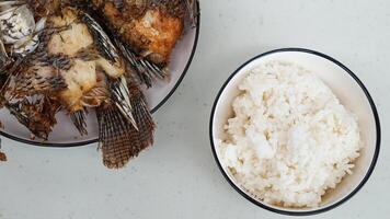 vit ris i en skål och friterad fisk på en vit tallrik är eras på de tabell foto
