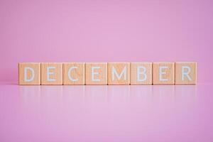 trä- block form de text december mot en rosa bakgrund. foto