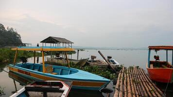 semarang, 7 april 2023 - fiske båtar på de stränder av rawa pening sjö. skön se av rawa pening sjö och de merbabu och telomoyo berg. fiskare på rawa pening sjö. foto