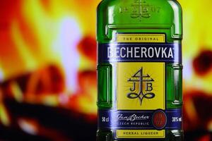 Kiev, ukraina - Maj 4, 2022 becherovka original- alkohol flaska på trä- tabell med röd öppen spis foto