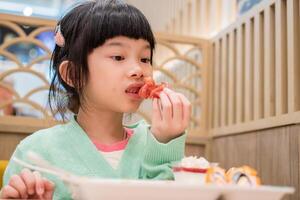 söt liten asiatisk barn flicka äter mat foto