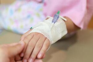 mor innehav barn hand med salin iv lösning i sjukhus foto