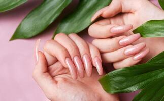 kvinna händer med rosa nagel design håll grön löv foto